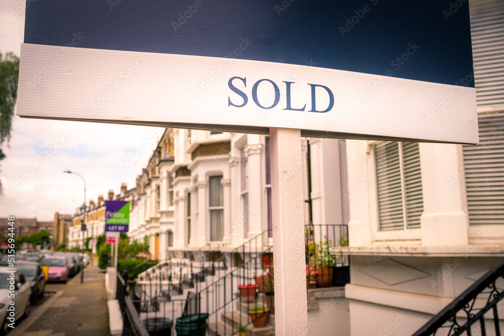 Estate agent SOLD sign on street of terraced houses