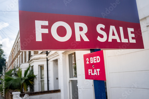 Estate agent 2 Bed Flat For Sale sign on street of houses- UK 