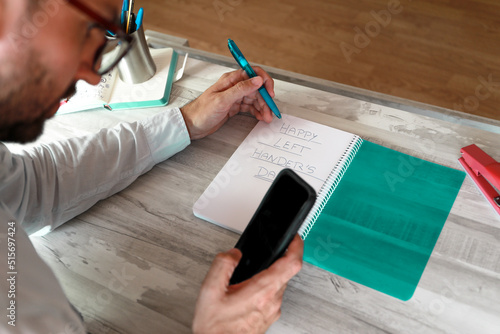 A boy writing with his left hand in a notebook for the international left-handed people's day.
