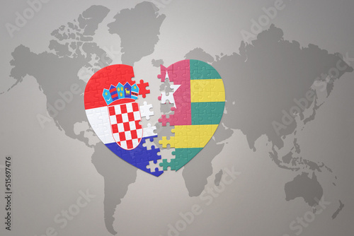 puzzle heart with the national flag of croatia and togo on a world map background.Concept.