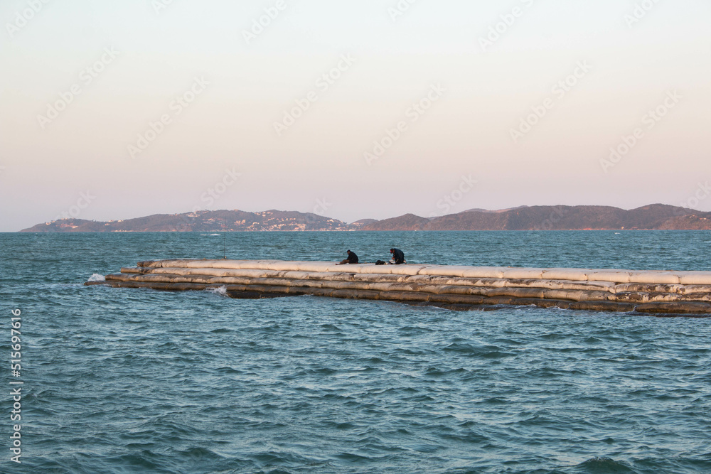 Turtle channel at sunset with two people fishing in Buzios, Brazil. fishing in Buzios, Brazil.