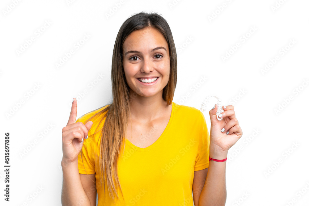 Young caucasian woman holding invisible braces isolated on white background pointing up a great idea Young caucasian woman holding invisible braces isolated on white background pointing up a great idea