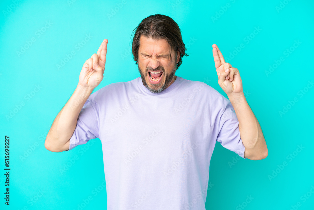 Senior dutch man isolated on blue background with fingers crossing Senior dutch man isolated on blue background with fingers crossing