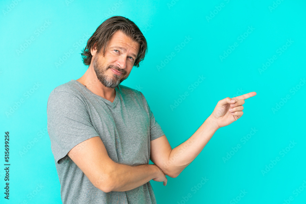 Senior dutch man isolated on blue background pointing finger to the side Senior dutch man isolated on blue background pointing finger to the side