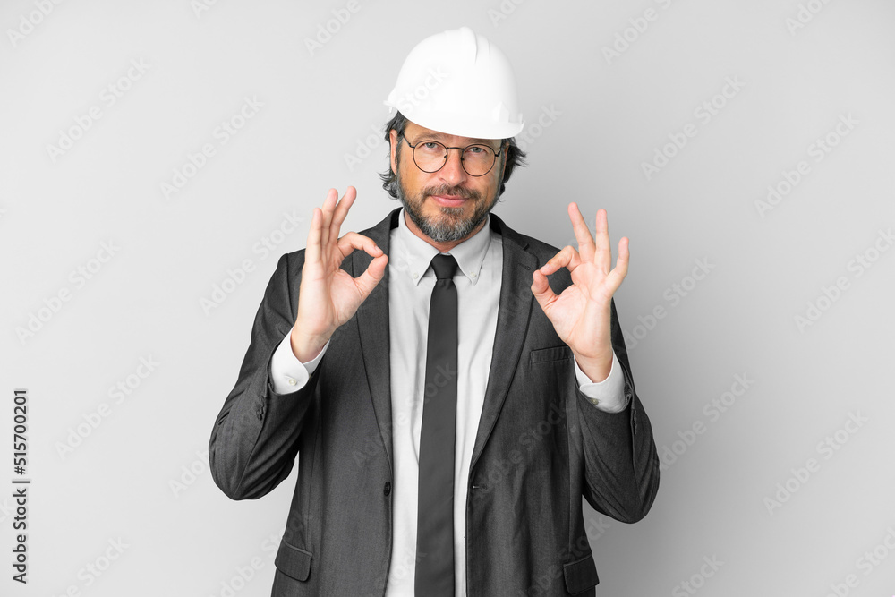 Young architect man with helmet over isolated background showing an ok sign with fingers Young architect man with helmet over isolated background showing an ok sign with fingers