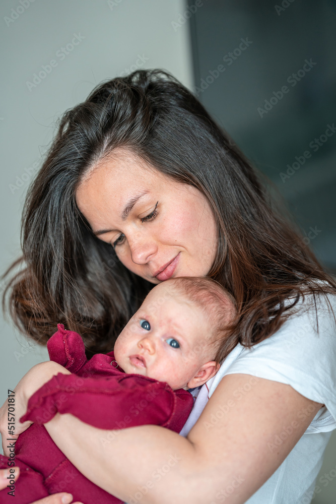 A newborn baby in the arms of his mother. Mother gently cuddles her baby A newborn baby in the arms of his mother. Mother gently cuddles her baby