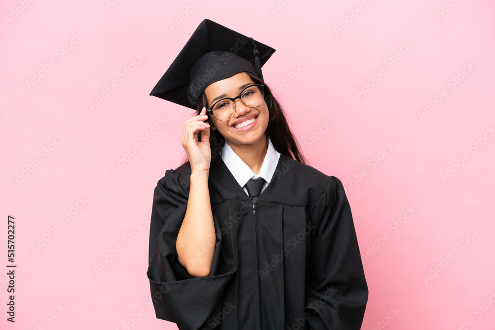 Young university Colombian woman graduate isolated on pink background with glasses and happy Young university Colombian woman graduate isolated on pink background with glasses and happy