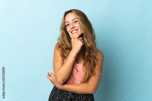 Young blonde woman isolated on blue background happy and smiling