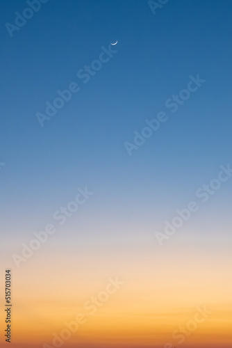 Photo Clear blue and orange sunset sky with crescent moon.