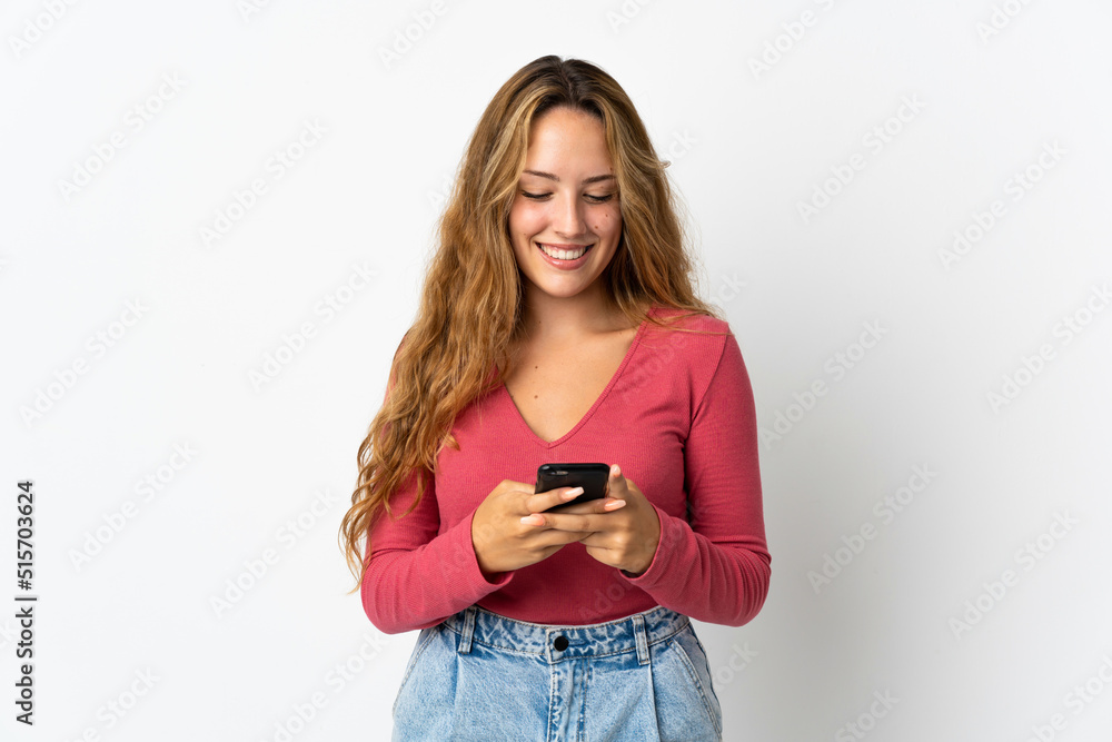 Young blonde woman isolated on blue background sending a message with the mobile Young blonde woman isolated on blue background sending a message with the mobile