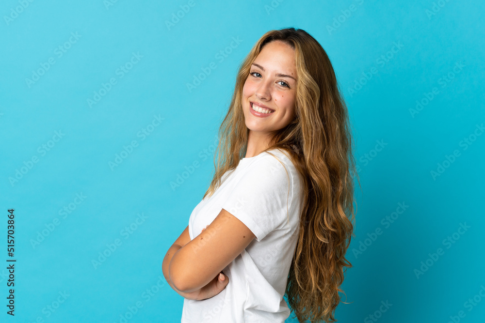 Young blonde woman isolated on blue background with arms crossed and looking forward Young blonde woman isolated on blue background with arms crossed and looking forward