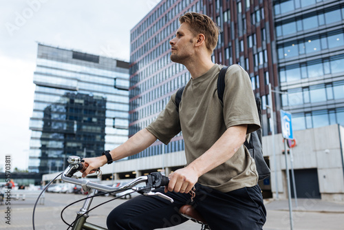 Young man riding a bike. Sustainable micro mobility transport New way of inclusive cities mobility. Green transportation. Sustainable climate neutral city goals. Green mobility and transportation