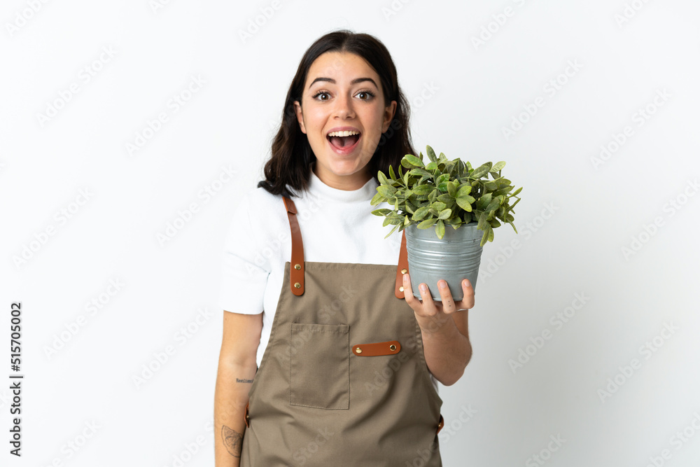 Young caucasian woman holding a plant isolated on white background with surprise and shocked facial expression Young caucasian woman holding a plant isolated on white background with surprise and shocked facial expression
