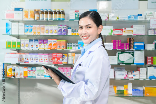 Portrait of female pharmacist using tablet in a modern pharmacy drugstore.