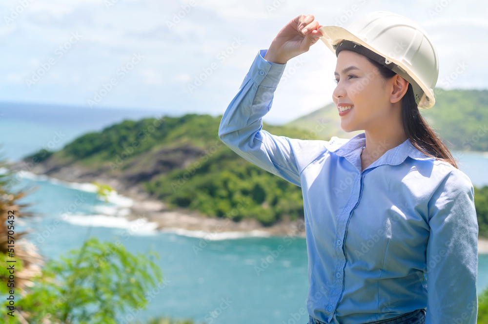 Female engineer working on the seaside wearing a protective helmet . Female engineer working on the seaside wearing a protective helmet .