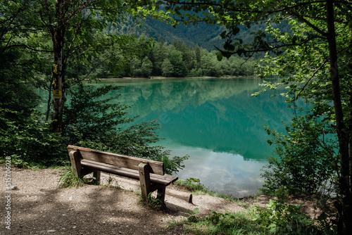 wooden bench by the lake in austria mountains with crystal clear water reflection like a mirror