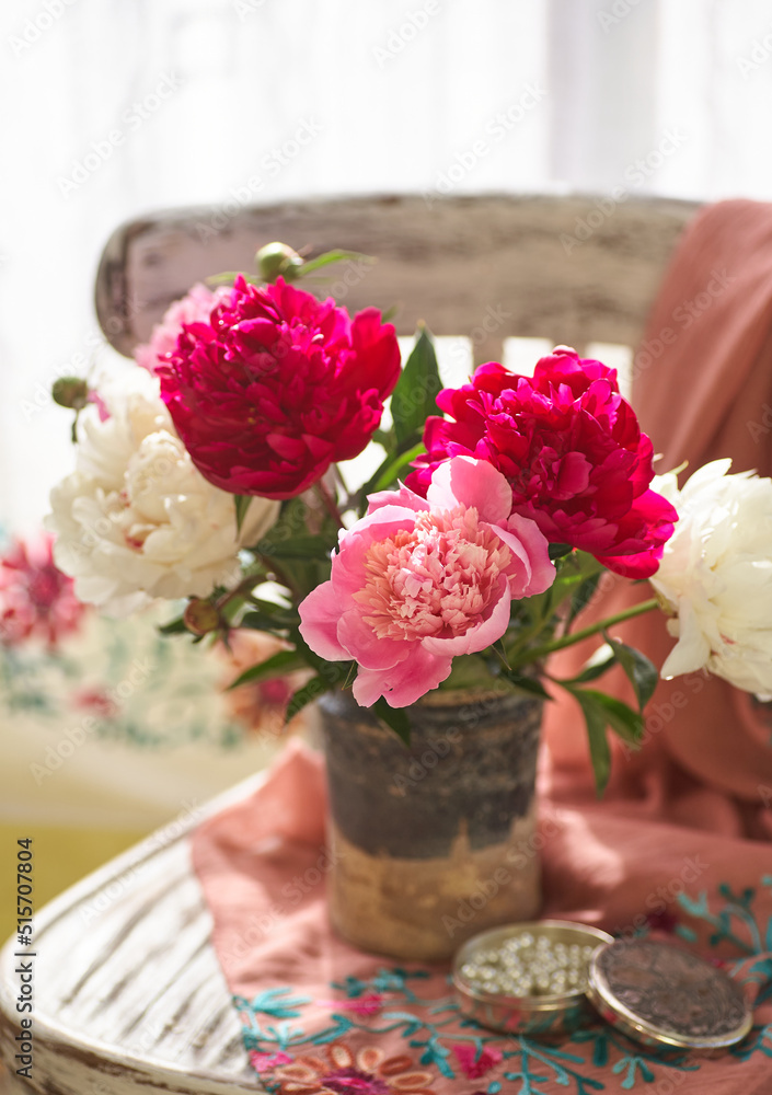 Still life with white and pink peonies in a old ceramic vase on vintaje chair