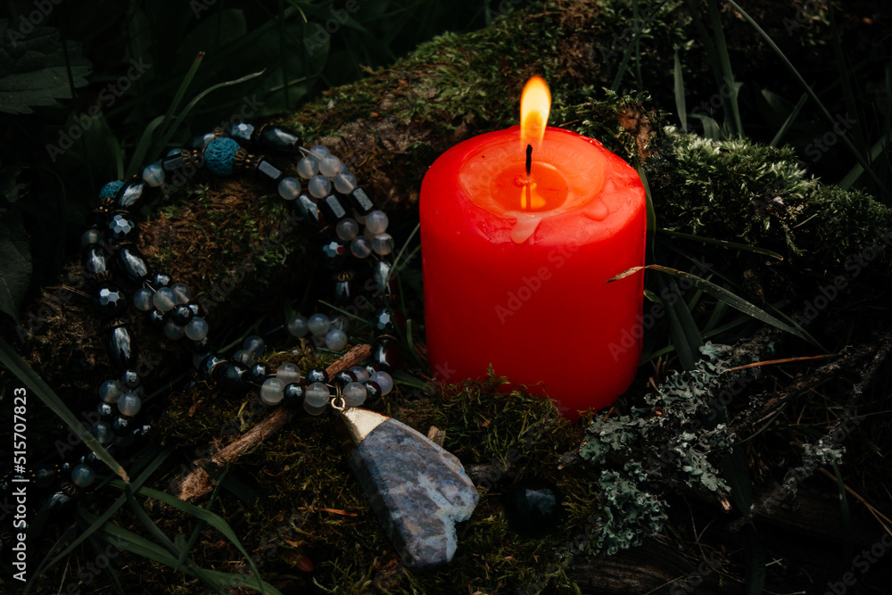 burning candle, a symbol of the moon, an amulet lying on the moss on a dark  natural background. pagan wiccan, slavic traditions. Witchcraft, esoteric  spiritual ritual for mabon, halloween, samhain. Photos