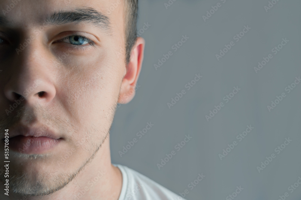 Portrait of beautiful young man with blue eyes, half face, space for text Portrait of beautiful young man with blue eyes, half face, space for text
