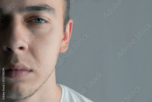 Portrait of beautiful young man with blue eyes, half face, space for text