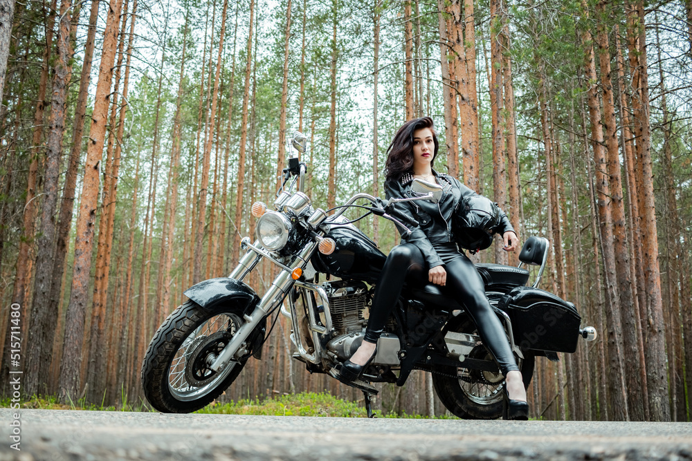 A girl in tight black leather sits on a motorcycle. A girl in tight black leather sits on a motorcycle.