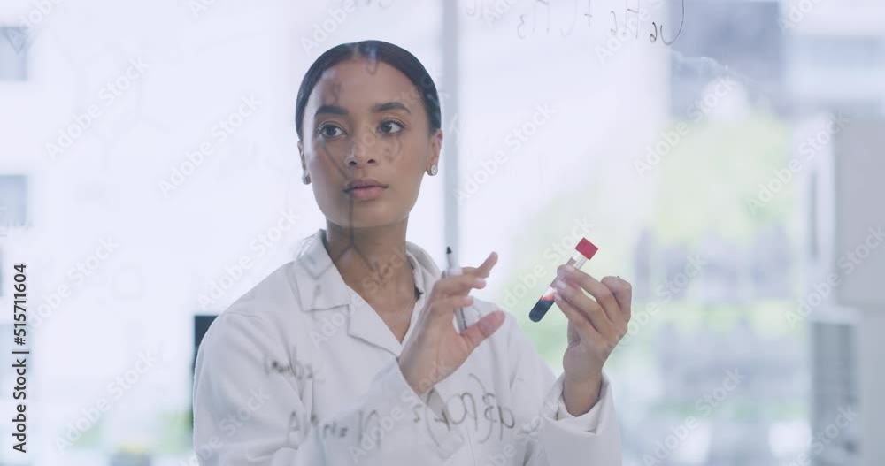 Female scientists writing formula on a clear glass board and holding a blood sample in a medical research facility. Biochemist pathologist developing cure to monkeypox virus while working in lab Female scientists writing formula on a clear glass board and holding a blood sample in a medical research facility. Biochemist pathologist developing cure to monkeypox virus while working in lab