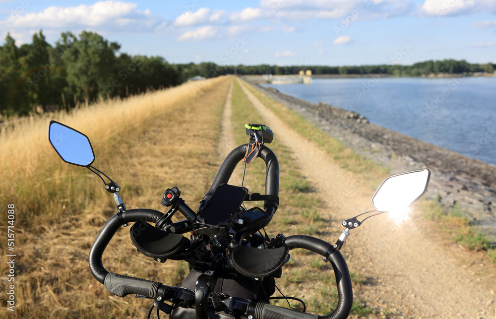 Kierownica wielopoziomowa roweru na polnej drodze wału wzdłóż jeziora. - obrazy, fototapety, plakaty 