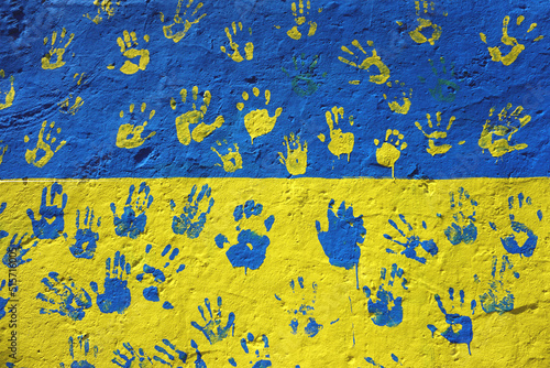 Concrete wall in the colors of the Ukrainian flag with handprints
