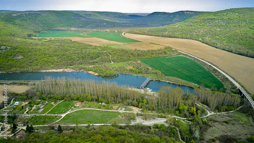 Aerial photography from a drone. View of green fields, rocky mountains and a river in a valley, on a sunny day with clear blue skies. Aerial photography from a drone. View of green fields, rocky mountains and a river in a valley, on a sunny day with clear blue skies.
