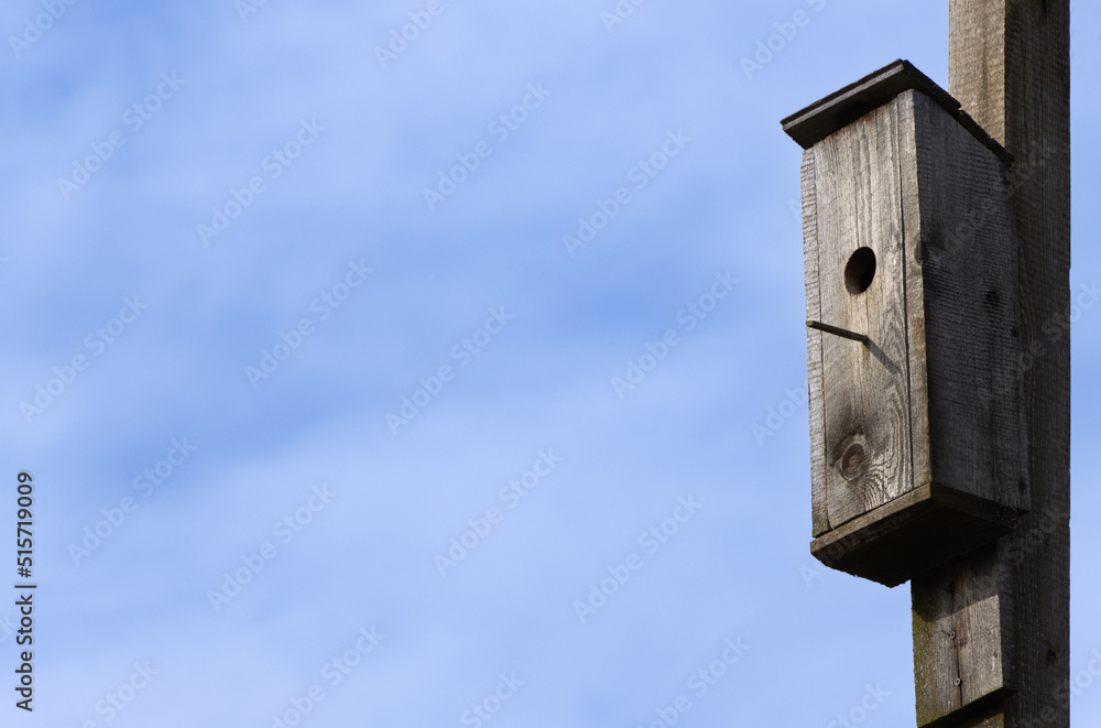 Old wooden birdhouse. Blue sky on the background. Old wooden birdhouse. Blue sky on the background.