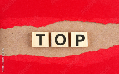 TOP word on wooden cubes on red torn paper , financial concept background