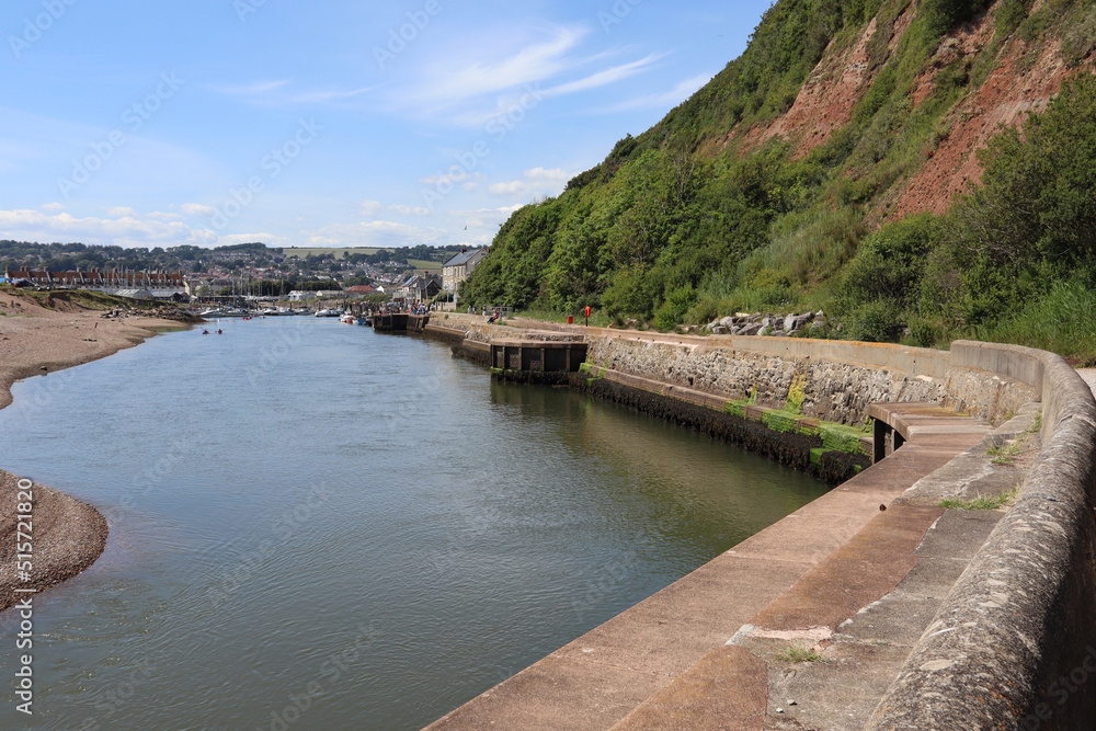 The river Axe flows quickly as it travels towards the sea looking back towards the marina and the yacht club The river Axe flows quickly as it travels towards the sea looking back towards the marina and the yacht club