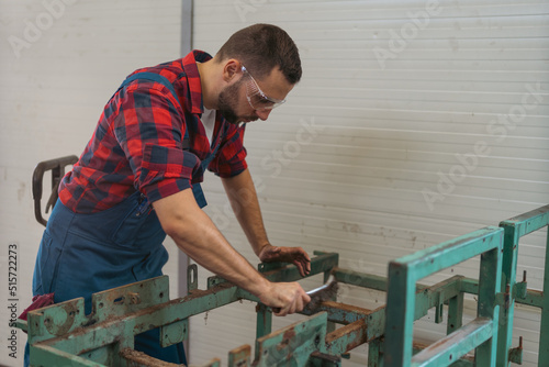 Young caucasian worker in repair shop cleaning old frame with wire brush