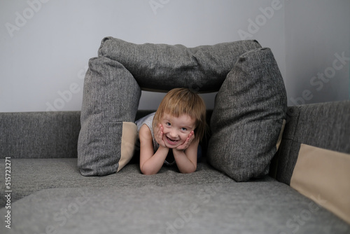 funny European child playing with pillows on couch