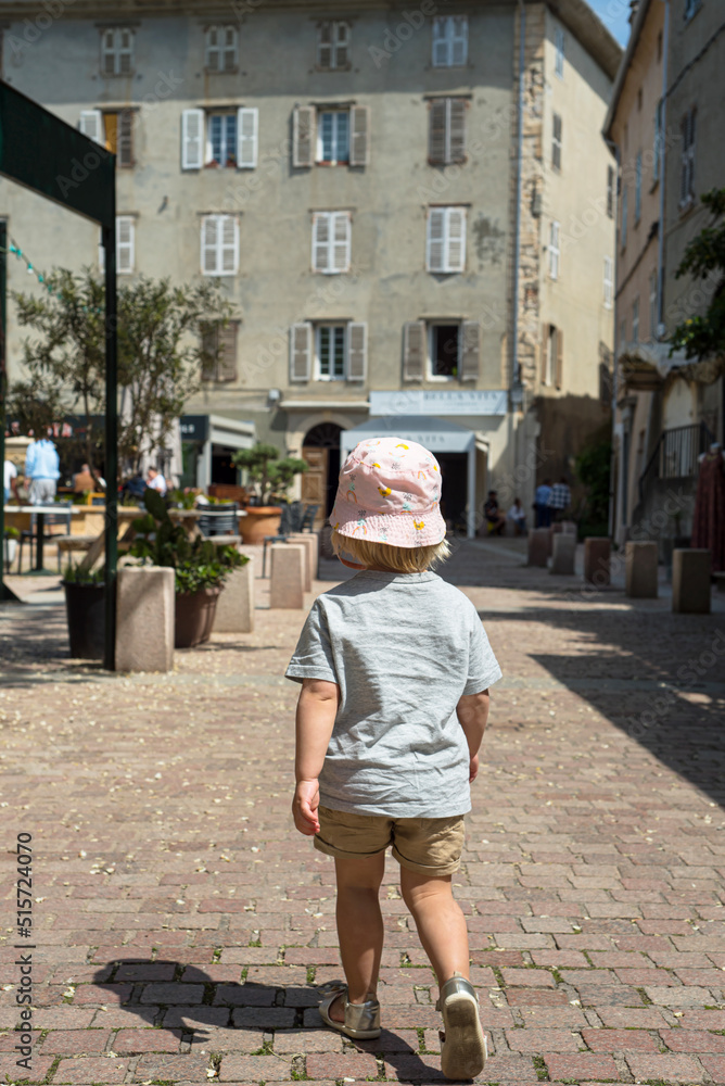 A little child walking on the paved street of the old Corsican Saint Florent city. France 2022