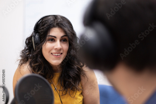 Close-up of smiling caucasian female radio announcer having a conversation with a person who is out of focus. Space for text. photo