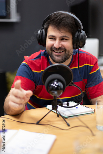 Portrait of smiling young caucasian man with headphones working in radio station. Announcer, commentator, live broadcast.