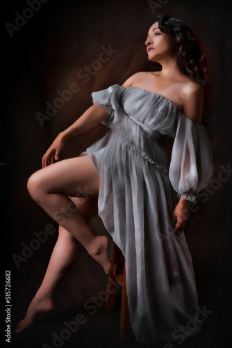 Beautiful latin woman in an antique dress, she is posing sitting she is very comfortable, low key