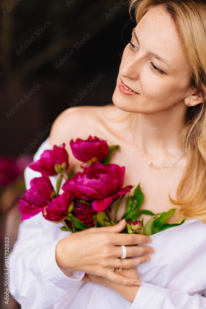tenderness. a blonde woman in a white shirt and a bouquet of peonies. tenderness. a blonde woman in a white shirt and a bouquet of peonies.