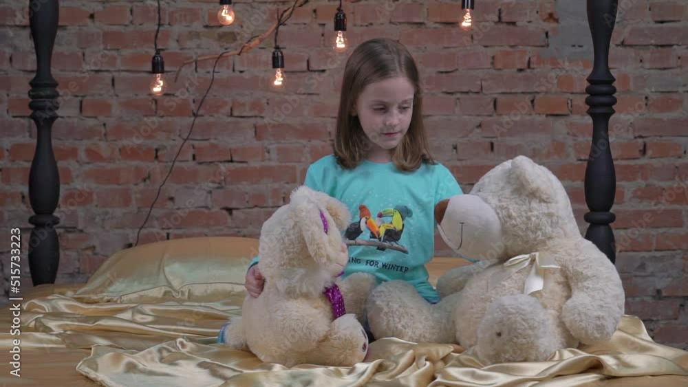 Slow Motion beautiful little girl playing with her teddy bear in bed ...