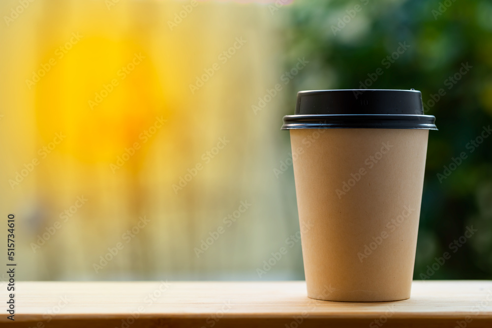 Disposable paper cups with a lid for tea, coffee to go or take away is on the table with golden sunrise background. Disposable paper cups with a lid for tea, coffee to go or take away is on the table with golden sunrise background.