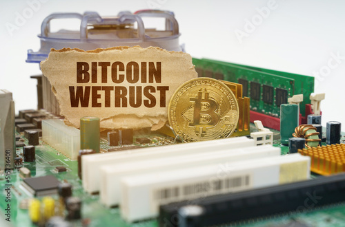 On the motherboard lies a bitcoin coin and a cardboard sign with the inscription - Bitcoin wetrust photo