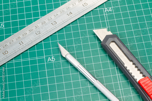 Quadro su tela Bisturí de acero, cutter y regla metálica sobre una tabla de cortar verde