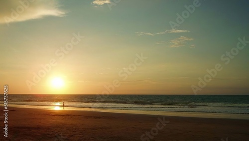SUNSET ON THE BEACH WITH TURQUOISE SEA AND CLEAR SKY WITH A MAN WATCHING THE SUNSET