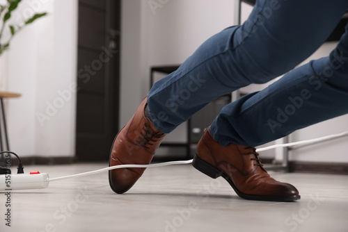 Man tripping over cord in office, closeup