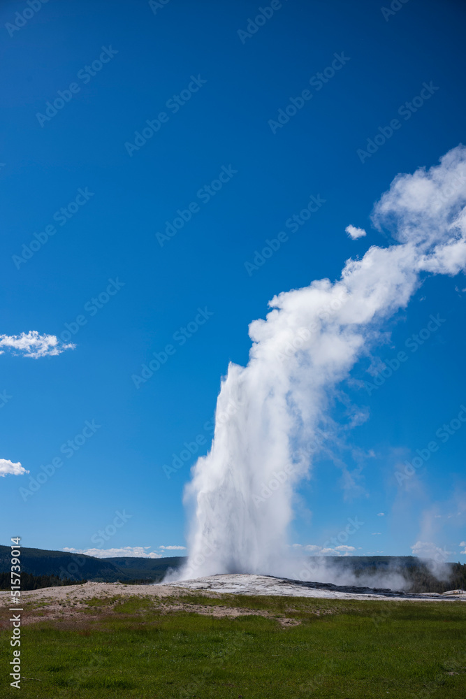 Visitors watch the famous geyser Old Faithful on a sunny day at Yellowstone National Park, which is the first national park in the U.S.