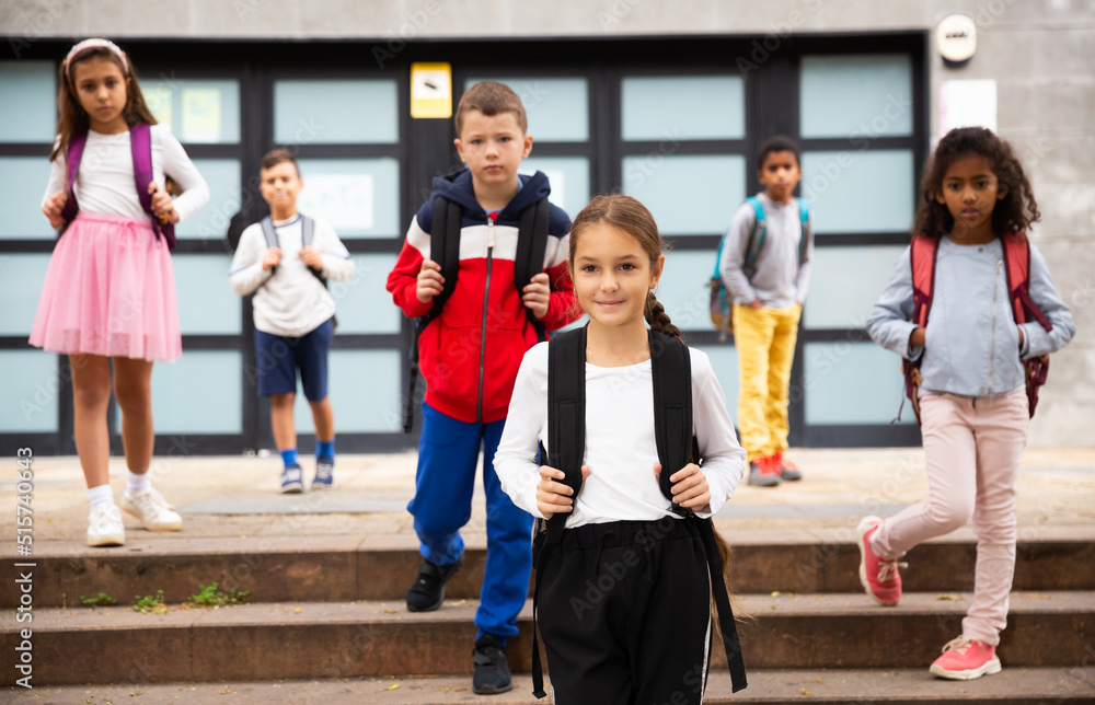 Portrait of smiling schoolgirl standing on the street, kids on background