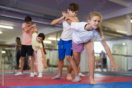 Group of young girls and boys training self-defence moves during group training.