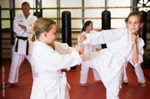 Sportive children working in pair mastering new karate moves during group class