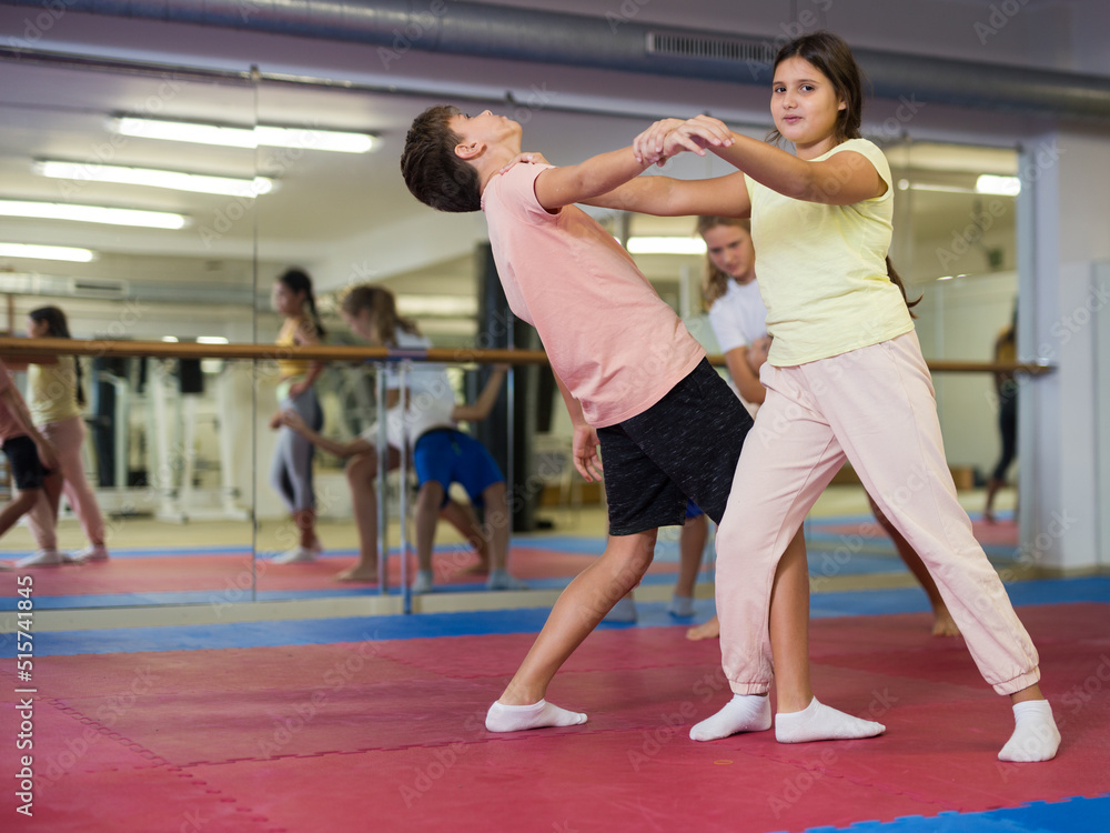 Fototapeta premium Kids exercising self-protection moves during group training in gym.